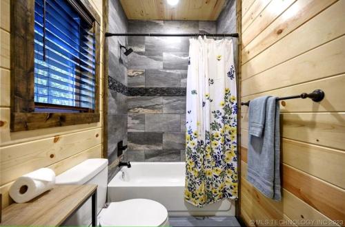 a bathroom with a toilet and a shower curtain at Bear with Me Cabin in Broken Bow in Broken Bow