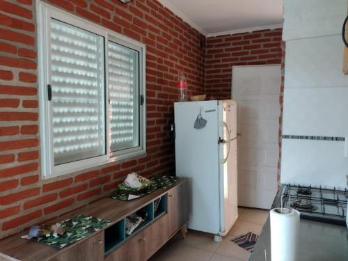 a kitchen with a refrigerator and a brick wall at Casaquinta grande con pileta y parrilla in Camba Punta