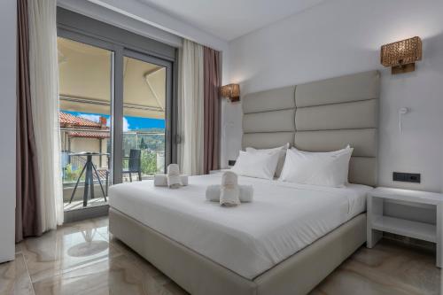 a bedroom with a large white bed and a balcony at Imagine Studios in Paliouri