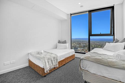 two beds in a room with a large window at Sky-High Villa with Wide Ocean Views - Pet Friendly in Gold Coast