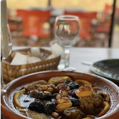 a bowl of food on a table with a wine glass at Panoramic Desert Camp with jeep pickup included in Merzouga