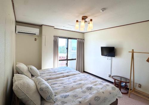 a bedroom with a large bed and a window at ビーチサイドペンションみーばる in Nanjo