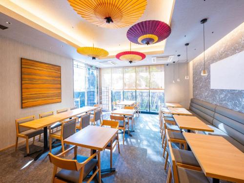 名古屋市にあるアパホテル 〈名古屋駅前南〉の木製のテーブルと椅子と窓のあるレストラン