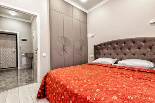 a bedroom with a large bed with a red bedspread at Expo Elite Apartments in Astana