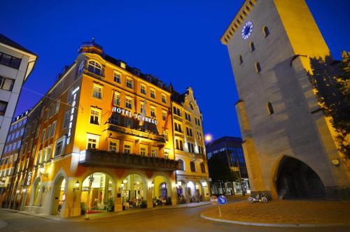 un bâtiment jaune avec une tour d'horloge à côté d'une rue dans l'établissement Hotel Torbräu, à Munich