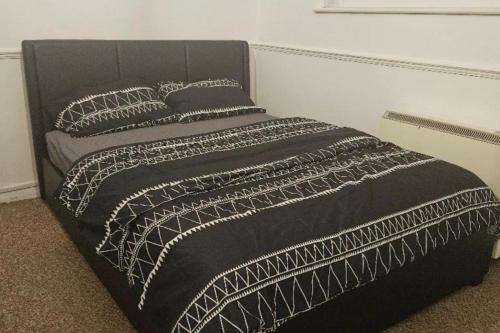 a black bed with a black and white blanket at 1 Bed House Sleeps 2 -Free Parking -Tv in Romford