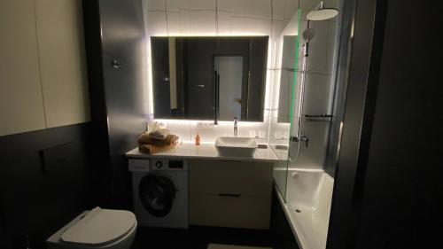 een badkamer met een wastafel, een toilet en een spiegel bij ARĞYN Apartments, 3-BR Central in Astana