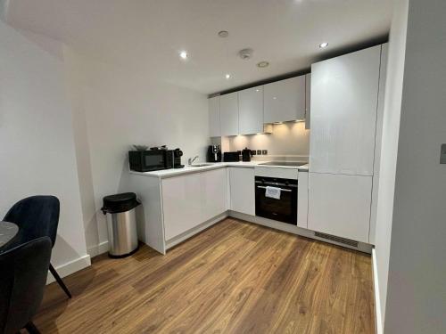a kitchen with white cabinets and a wooden floor at 1 Bed Serviced Apartment Bracknell 5 mins from station in Bracknell