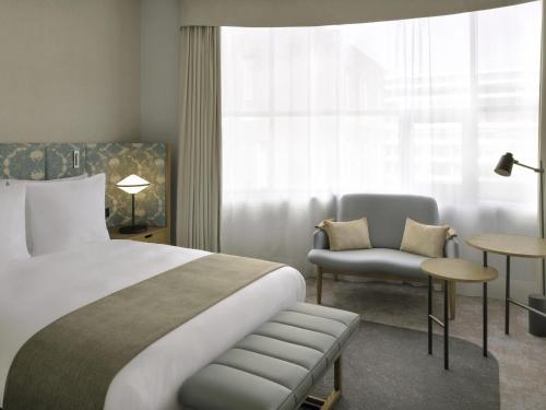 a hotel room with a bed and a chair and a window at Mövenpick Hotel The Hague in The Hague