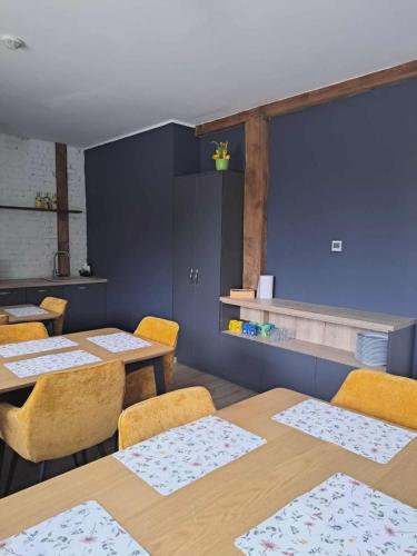 a dining room with two tables and yellow chairs at Stary Młyn in Glinik
