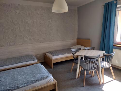 a room with two beds and a table and chairs at Agroturystyka Pod Orzechem in Lubiąż