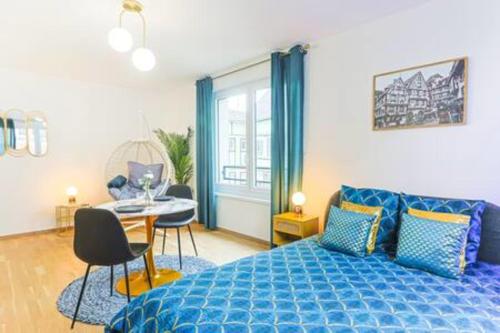 a bedroom with a blue bed and a table and chairs at Le Venise I Private Parking I Spacious & Bright in Colmar