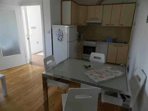 a kitchen with a glass table with chairs and a refrigerator at Apartments Belvedere Lovran in Lovran
