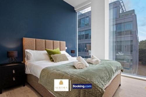 ein Schlafzimmer mit einem Bett und einem großen Fenster in der Unterkunft Stylish 2BDR Apartment With Cinema, Gym and Free Parking By Aurora WorkNest Short Lets & Serviced Accommodation London in Kew Bridge