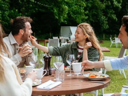 マフリエにあるHotel Novotel Domaine de Maffliers - Paris Val-d'Oiseのテーブルの周りに座って食事をとる人々のグループ