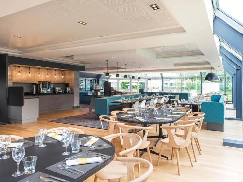 Un restaurante con mesas y sillas y un bar. en Novotel Lille Aéroport, en Lesquin