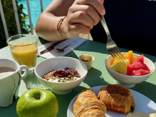 una persona que sostiene un tenedor sobre un plato de comida para el desayuno en ibis Styles Marseille Aéroport, en Vitrolles