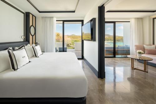 a bedroom with a large bed and a living room at BLESS Ibiza Cala Nova - The Leading Hotels of the World in Es Cana