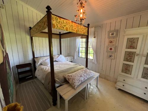 a bedroom with a canopy bed with a chair and a chandelier at Capilla-Casa de campo in Capilla del Señor