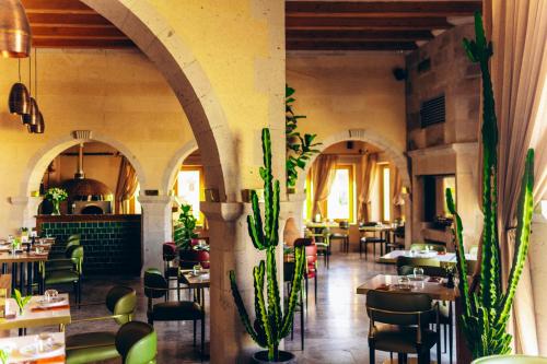 a restaurant with tables and chairs and plants at Millstone Cave Suites Hotel in Uchisar