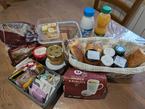 una mesa con una cesta de comida, bebidas y pan en PETIT MAS COSY DU BORD DE LOIRE a 15 MM DU PARC LE PAL, en Diou
