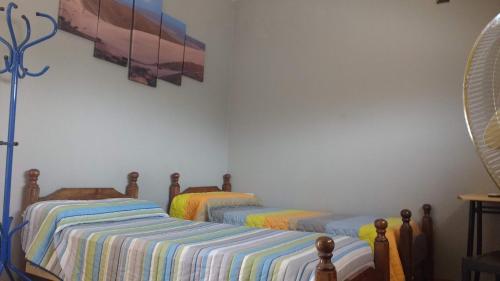 two twin beds in a bedroom with a painting on the wall at Abaucan alojamiento in Fiambala