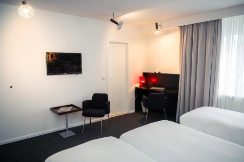 a hotel room with two beds and a desk at Hotel Queen Anne in Brussels