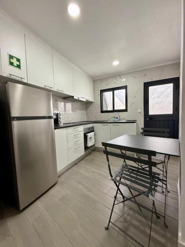 eine Küche mit Tisch und Edelstahlkühlschrank in der Unterkunft Canto da Maré in Ribeira Grande