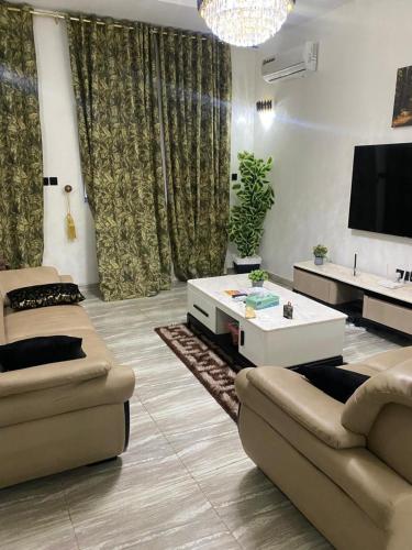 a living room with two couches and a tv at Bumcy Apartment in Ankuru