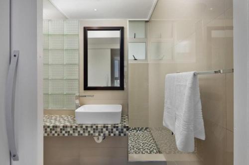 Un baño blanco con lavabo y espejo. en Ashley On Beach 1104 Prestige Style, en Strand