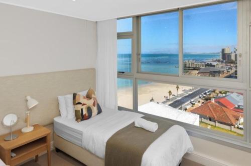 Un dormitorio con un gran ventanal con vistas a la playa. en Ashley On Beach 1104 Prestige Style, en Strand