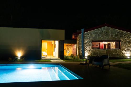 a swimming pool in front of a house at night at Casa Encosta do Monte in Póvoa de Lanhoso