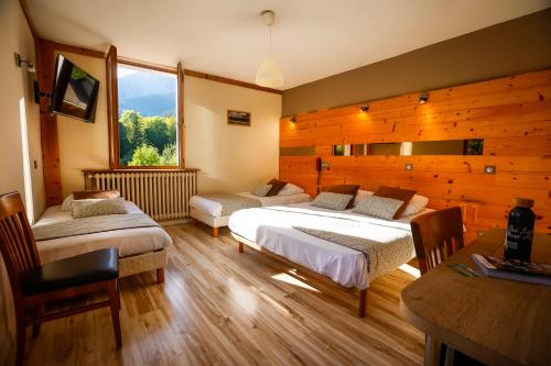 a bedroom with two beds and a large window at Logis Hôtel Au Gai Soleil du Mont-Aiguille in Chichilianne