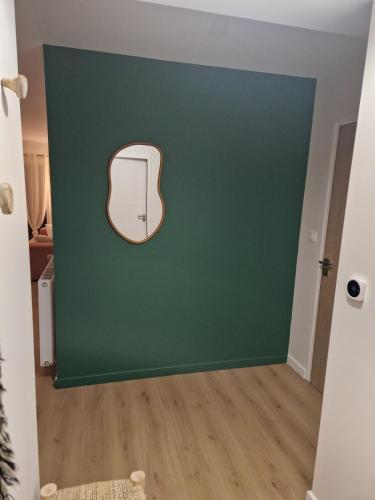 a room with a green wall and a mirror at 2 chambres, avec balcon, à 8 min des plages en voiture in Plérin