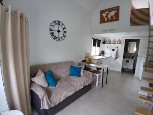 a living room with a couch and a clock on the wall at Petite Maison in Saint-André-les-Vergers