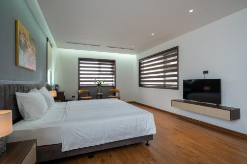 a bedroom with a white bed and a flat screen tv at Luxe Paradise Hotel Nguyen Khac Hieu in Hanoi