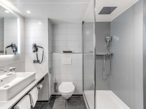 a bathroom with a shower and a toilet and a sink at Mercure Hotel Freiburg am Münster in Freiburg im Breisgau