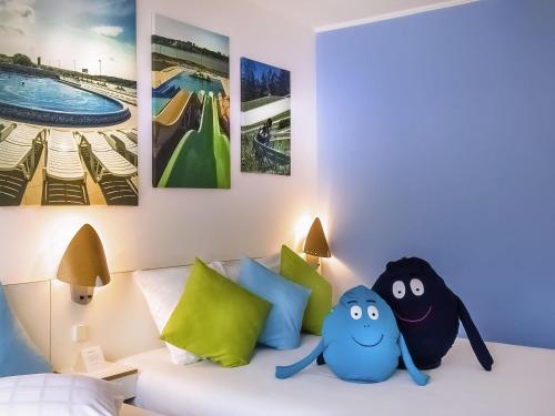 Un dormitorio con una cama con dos animales de peluche encima. en Novotel Poznań Malta, en Poznan