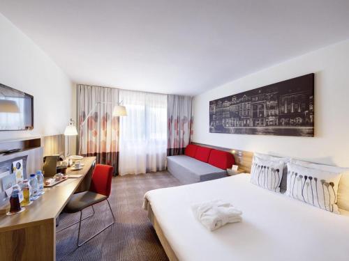 a hotel room with a large bed and a desk at Novotel Poznań Malta in Poznań