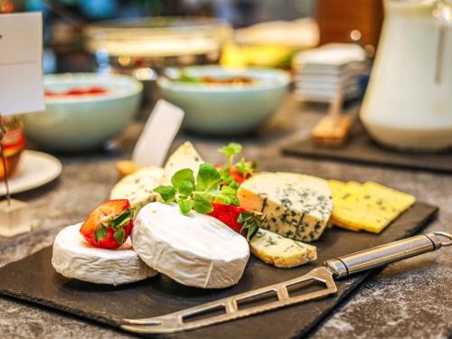 a table topped with cheese and fruit on a cutting board at Novotel Poznań Malta in Poznań