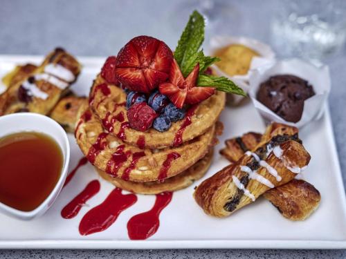 un plato de comida con gofres y fruta. en Novotel Cairns Oasis Resort, en Cairns
