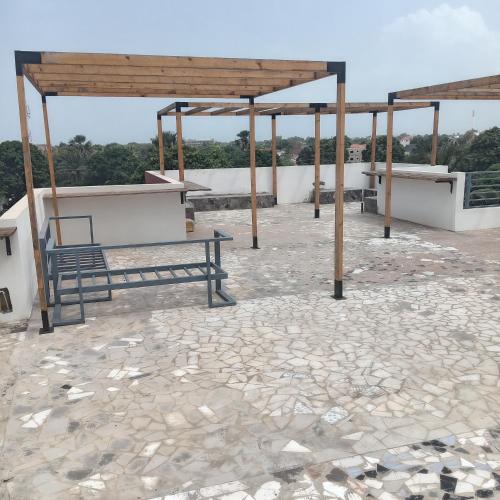 a pavilion with tables and benches on a stone patio at Comfort Corner in Amdalai