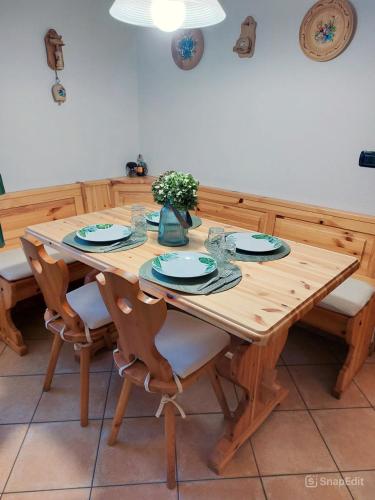 a wooden table with chairs and plates and a vase at Lo chalet di Lucky in Campodolcino