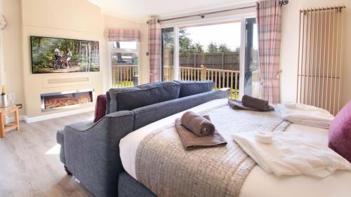 1 dormitorio con cama, sofá y chimenea en The Shrubbery Treehouse Park Facilities, en Milford on Sea