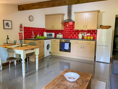 a kitchen with a table and a white refrigerator at Chestnut Cottage - 27636 in Darenth
