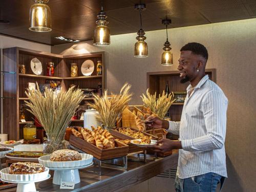 um homem segurando um prato de comida em uma padaria em Sofitel Strasbourg Grande Ile em Estrasburgo
