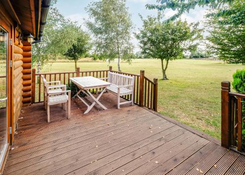 a wooden deck with two chairs and a table at Laxfield Lodges in Laxfield
