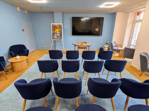 a room with blue chairs and a table and a screen at ibis Grenoble Centre Bastille in Grenoble