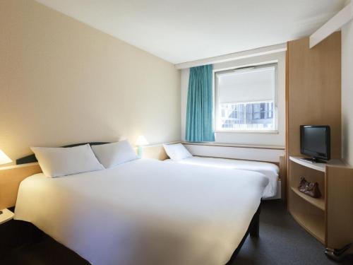 a hotel room with two beds and a window at ibis Lyon Est Bron in Bron