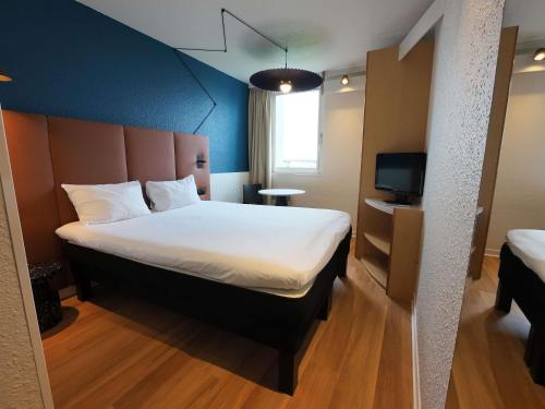 a hotel room with a large bed and a television at ibis Lyon Est Bron in Bron